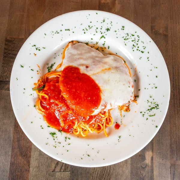 Chicken parmesan with melted mozzarella, marinara sauce, and spaghetti on a white plate.