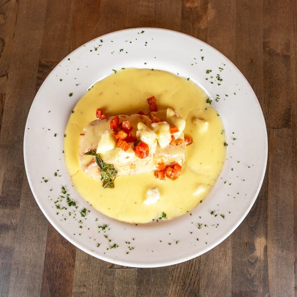 Chicken breast in a creamy yellow sauce, topped with diced tomatoes, mozzarella, and basil.