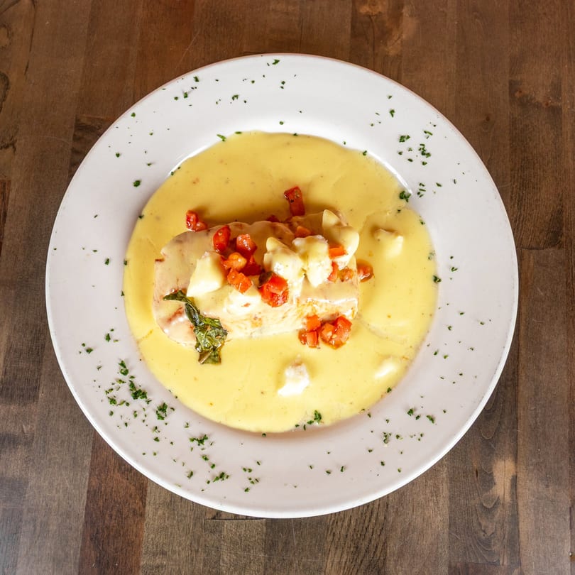 Chicken breast in a creamy yellow sauce, topped with diced tomatoes, mozzarella, and basil.