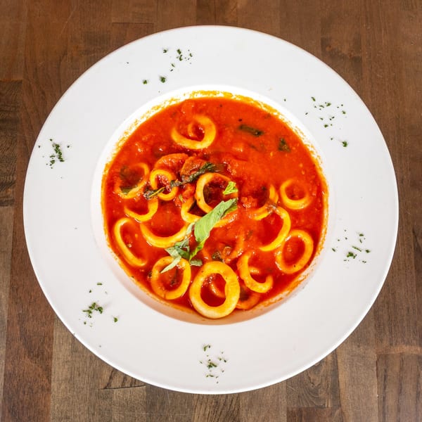 Calamari rings in a rich red tomato sauce, garnished with fresh basil and parsley.